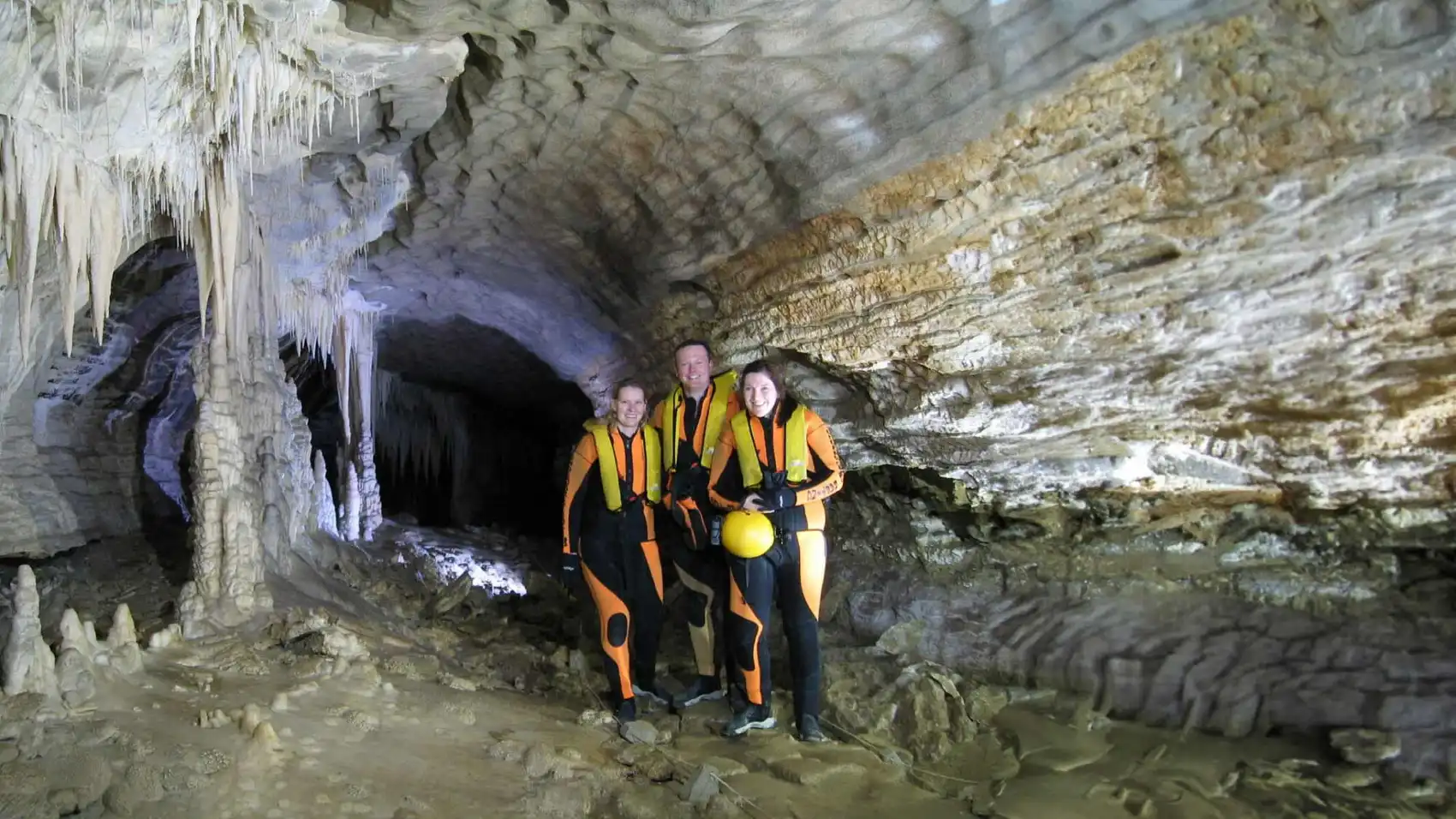 Three people posing for a photo in a cave