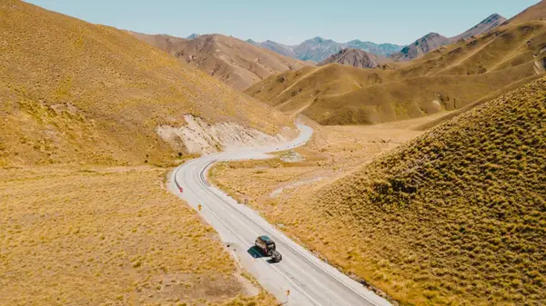 Wild Kiwi bus driving through Lindis Pass in New Zealand