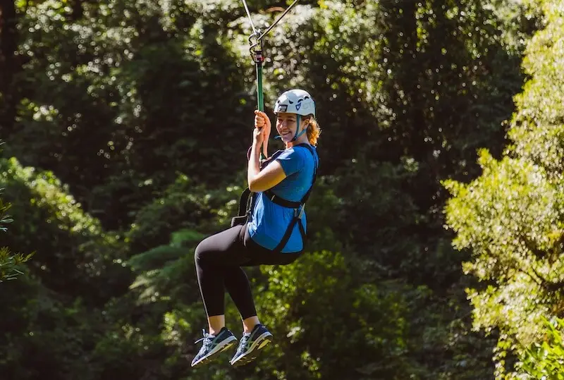 A woman zip-lining through rainforest on Rotorua New Zealand.