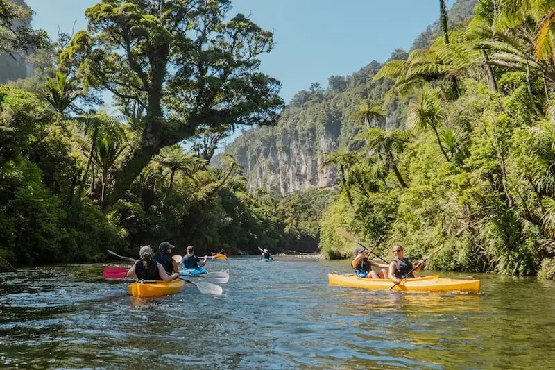 Photo of one of the best summer activities in New Zealand's South Island - kayaking in Punakaiki. Photo of a group of young travellers on an adventure road trip of New Zealand.