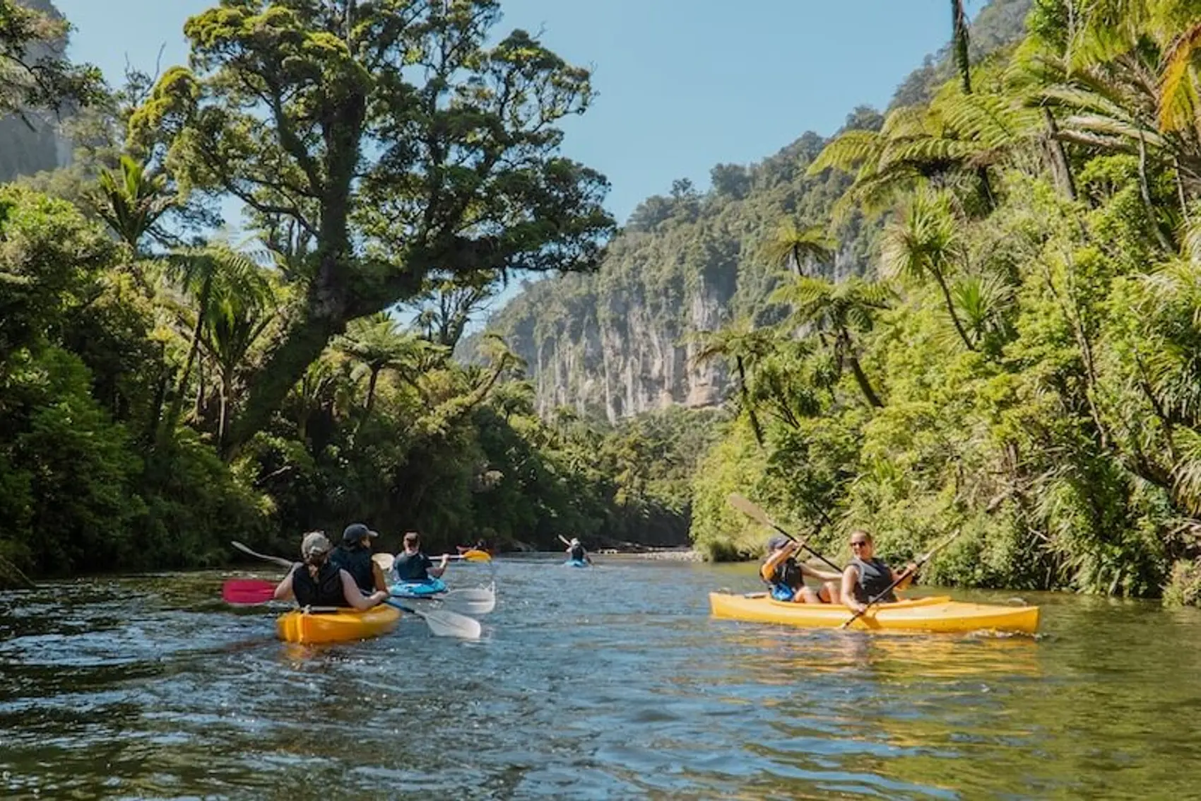 Photo of one of the best summer activities in New Zealand's South Island - kayaking in Punakaiki. Photo of a group of young travellers on an adventure road trip of New Zealand.