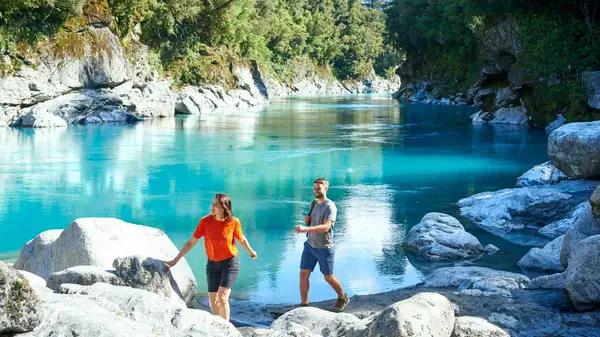 Couple walk next to the blue pools in Hokitika Gorge