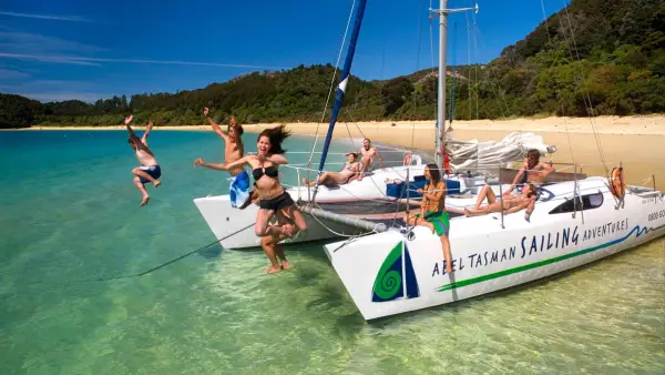 Group of people jump off a yacht in Abel Tasman National Park