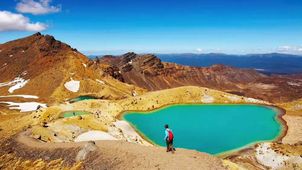 Person walks in front of the Emerald Lakes on the Tongariro Crossing