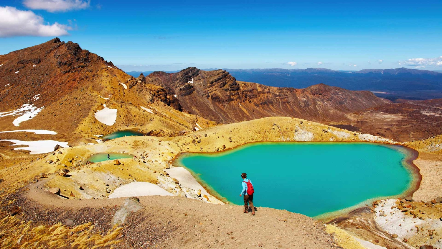 Person walking next to an alpine lake on the Tongariro Crossing