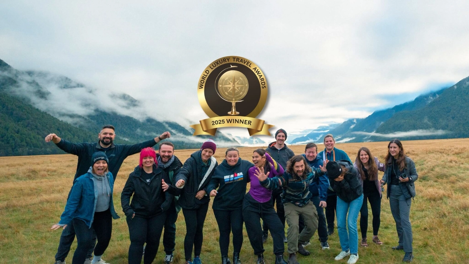 Wild Kiwi team celebrating being named Best Adventure Tour Company in New Zealand 2025 at the World Luxury Travel Awards, surrounded by mountain scenery on a small-group adventure tour.