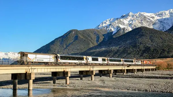 Tranz Alpine scenic rail train driving through mountains in New Zealand