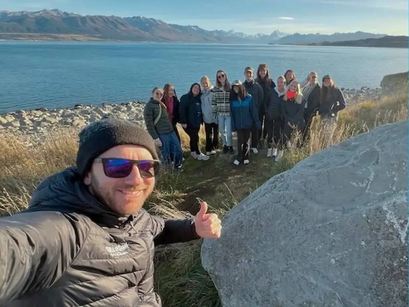 Wild Kiwi guide and travellers enjoying a small-group adventure tour by a South Island lake in New Zealand, reflecting the company’s focus on safety, comfort, and authentic travel experiences.