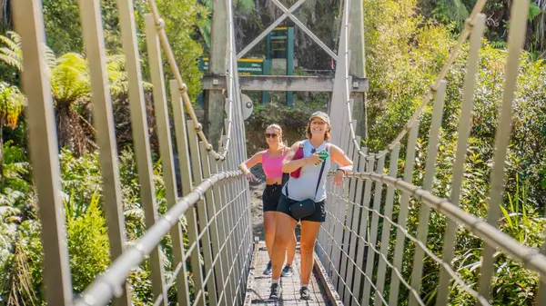 Two women pose for a photo on a bridge