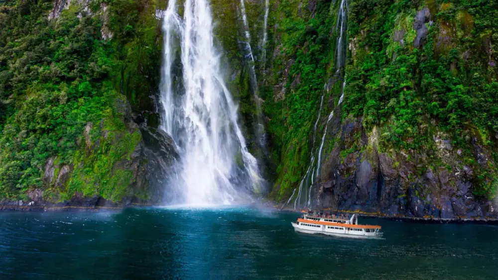 Boat by a waterfall in Milford Sound