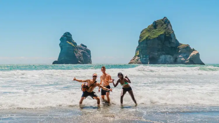 Group of friends pose for a photo on Wharariki Beach