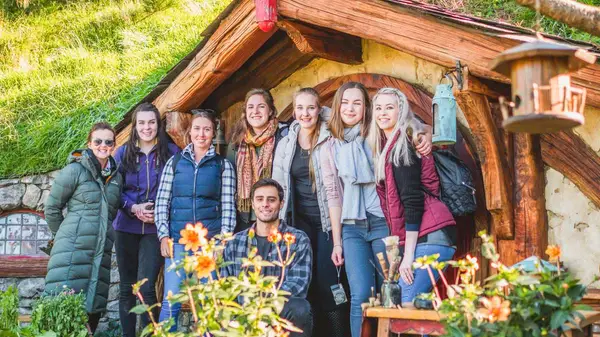 Group of people pose for a photo in front of a hobbit house