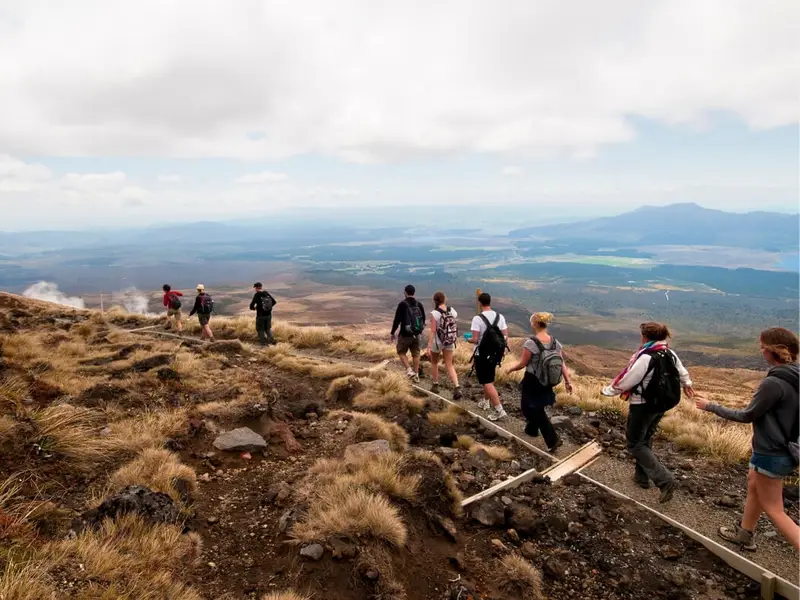 A group of travellers hiking across volcanic terrain on the Tongariro Alpine Crossing in Tongariro National Park, a top-rated New Zealand hiking trail and one of the most popular North Island day walks.
