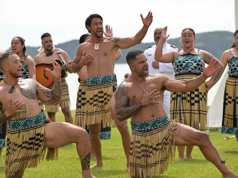 A Māori cultural performance on New Zealand’s North Island with performers in traditional dress beside a lake, representing one of the key reasons travellers may choose the North Island for Māori culture, geothermal landscapes and deeper cultural experiences when comparing North Island vs South Island New Zealand.