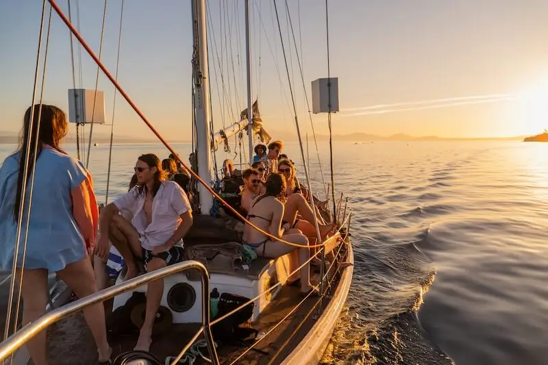 Photo of a group of happy people on a sustainable sailing boat tour on Lake Taupo. The group of young travellers enjoying one of the best New Zealand summer activities in the North Island.