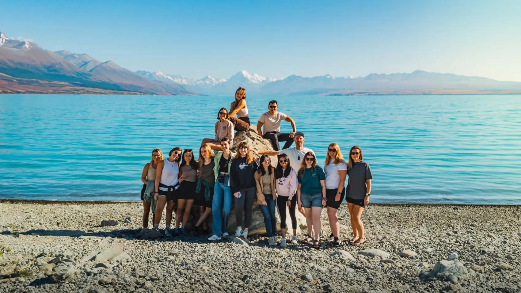 Group of people pose for a picture in front of Lake Tekapo