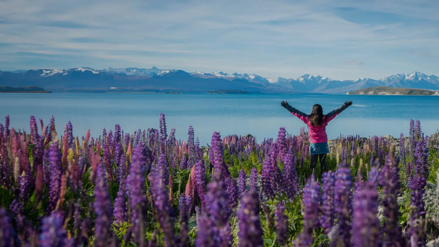 Woman with her arms out admiring the view at Lake Tekapo