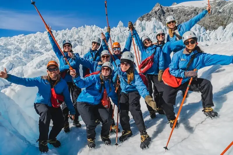 A group of youth travellers on an adventure tou of New Zealand. On a glacier heli-hike, one of the top New Zealand activites.