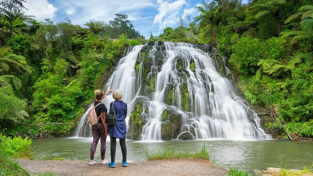 Two people looking at a waterfall in Karangahake Gorge in New Zealand