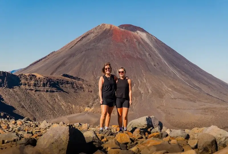 Photo of two girls standing before a volcano on the Tongariro Crossing in New Zealand.