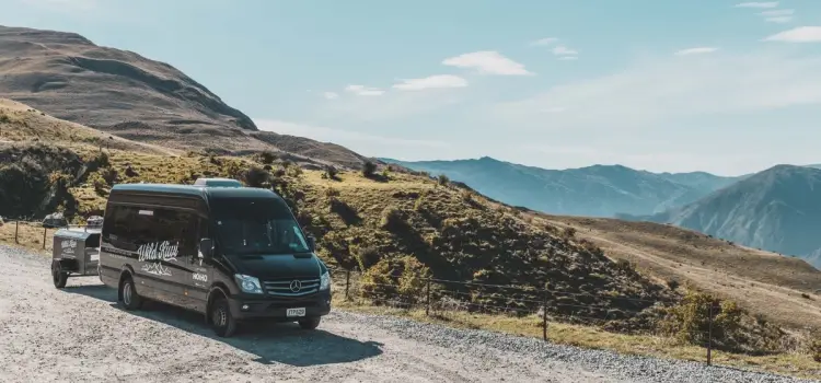 Wild Kiwi Tours vehicle parked at a beautiful overlook of mountains in New Zealand.