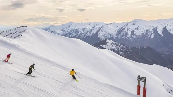 Group of people ski down Coronet Peak in New Zealand