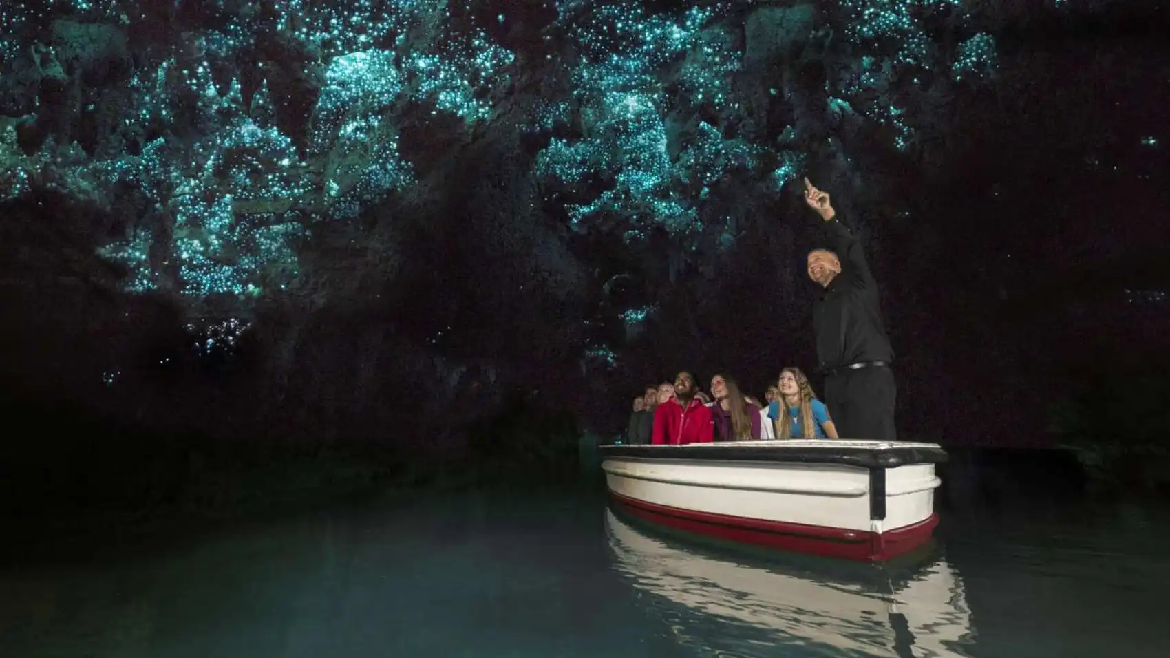 Group of people on a boat in a glowworm cave