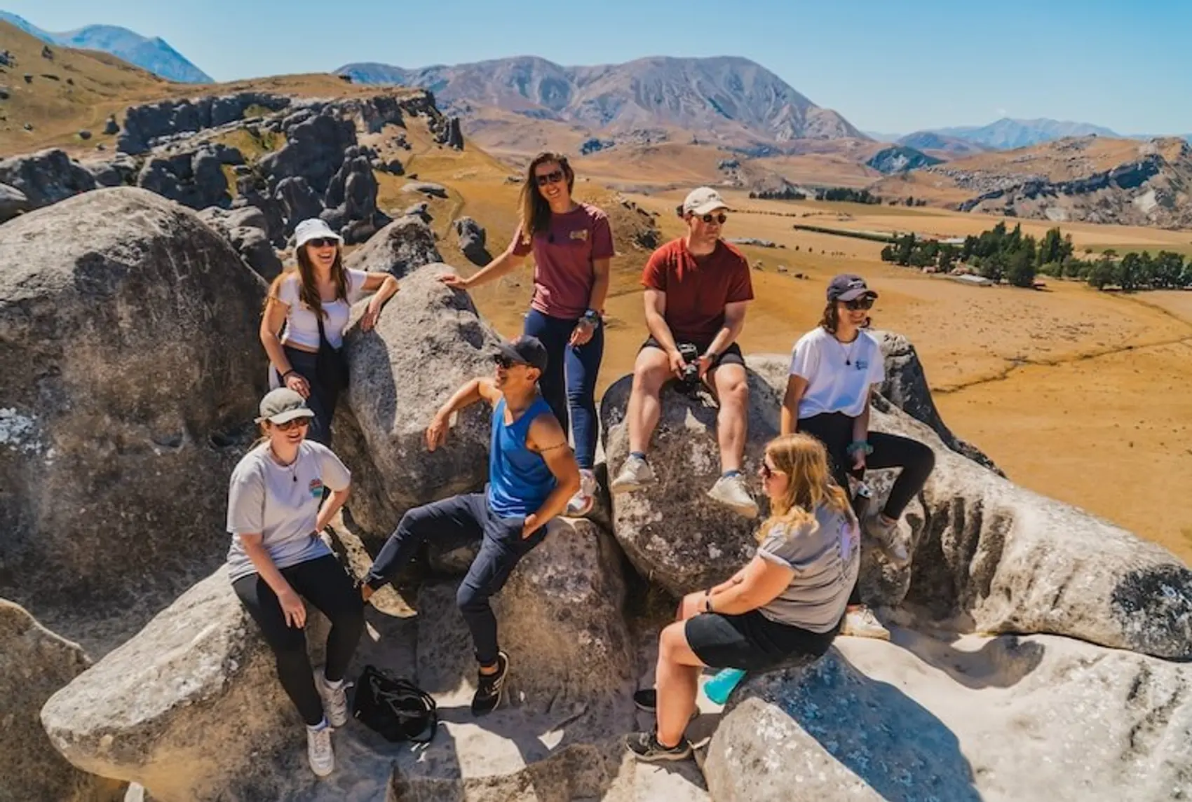 A group of travellers sit on giant boulders at Castle Rock in New Zealand.