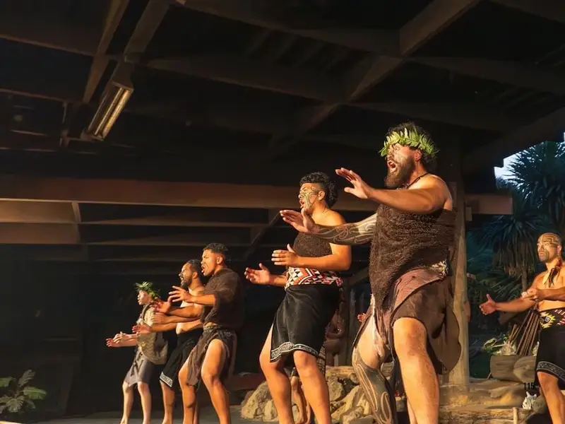 Māori performers presenting a traditional haka during a cultural show in Rotorua, New Zealand, wearing woven garments and tā moko face markings.