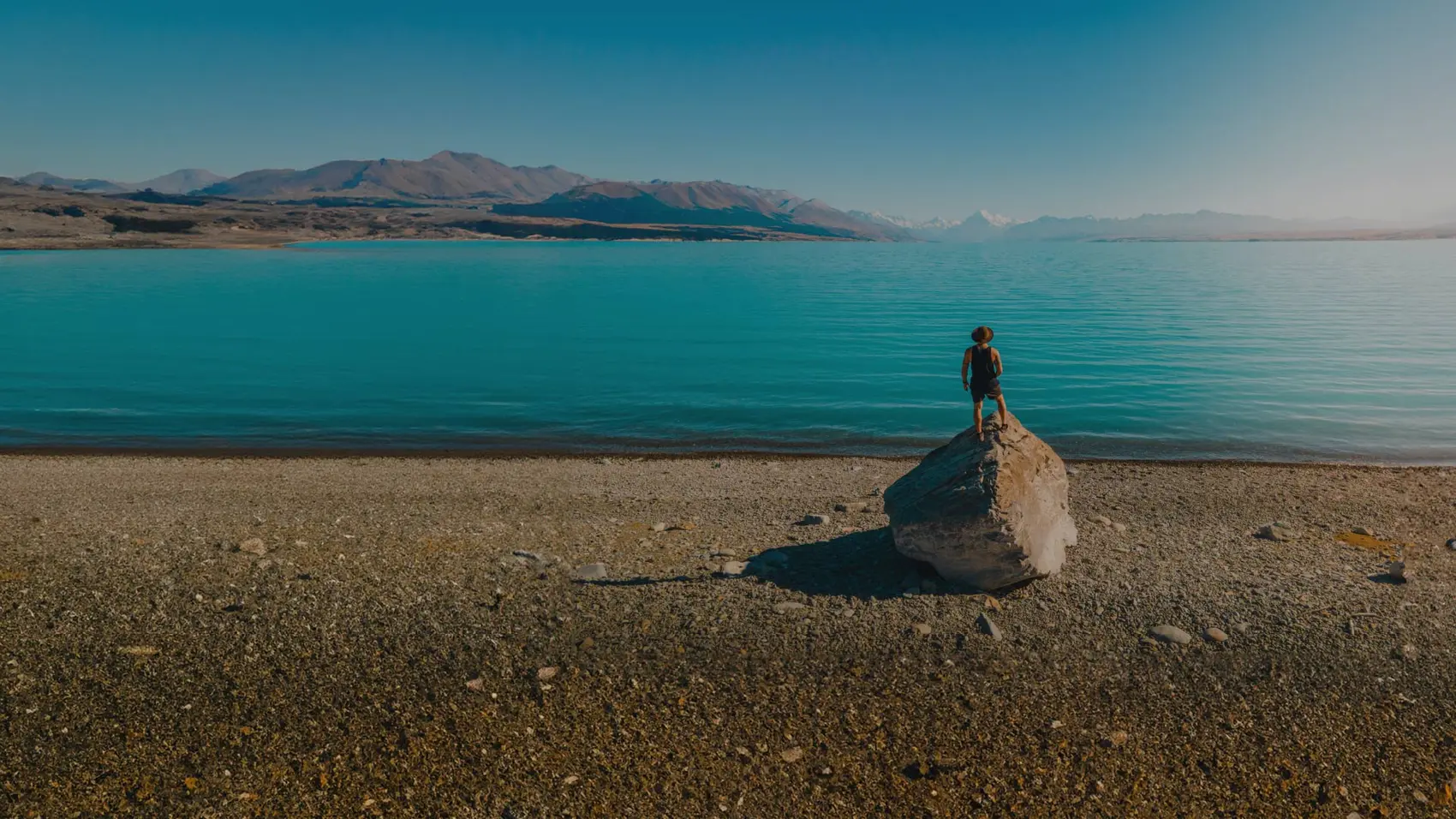 Man standing on a rock on the shore of Lake Tekapo