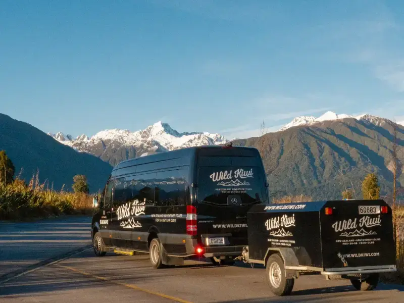 Wild Kiwi tour van parked in New Zealand’s South Island with snow-capped mountains in the background, highlighting small group winter travel, scenic road trip routes and an easy way to explore New Zealand beyond skiing.
