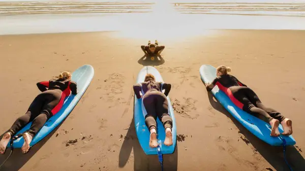 Three people learning to surf on the beach in Raglan