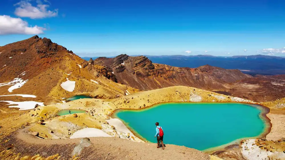 Person walking next to an alpine lake on the Tongariro Crossing