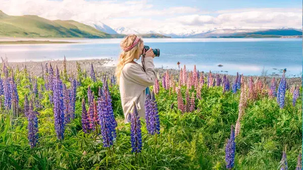 Woman taking a photograph at Lake Tekapo