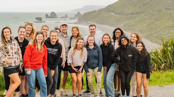 Group of people pose for a photo on the west coast of the south island