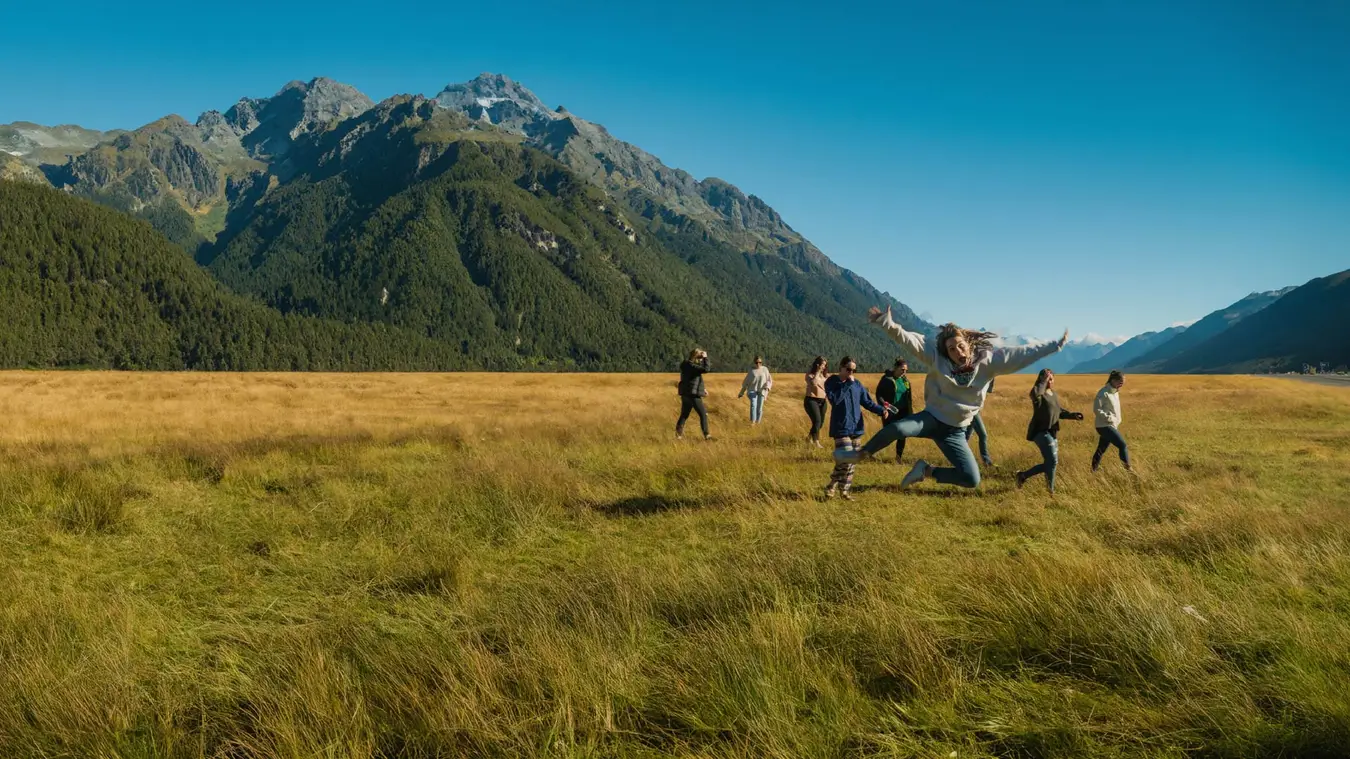 Woman jumps for joy in Fiordland National Park in New Zealand