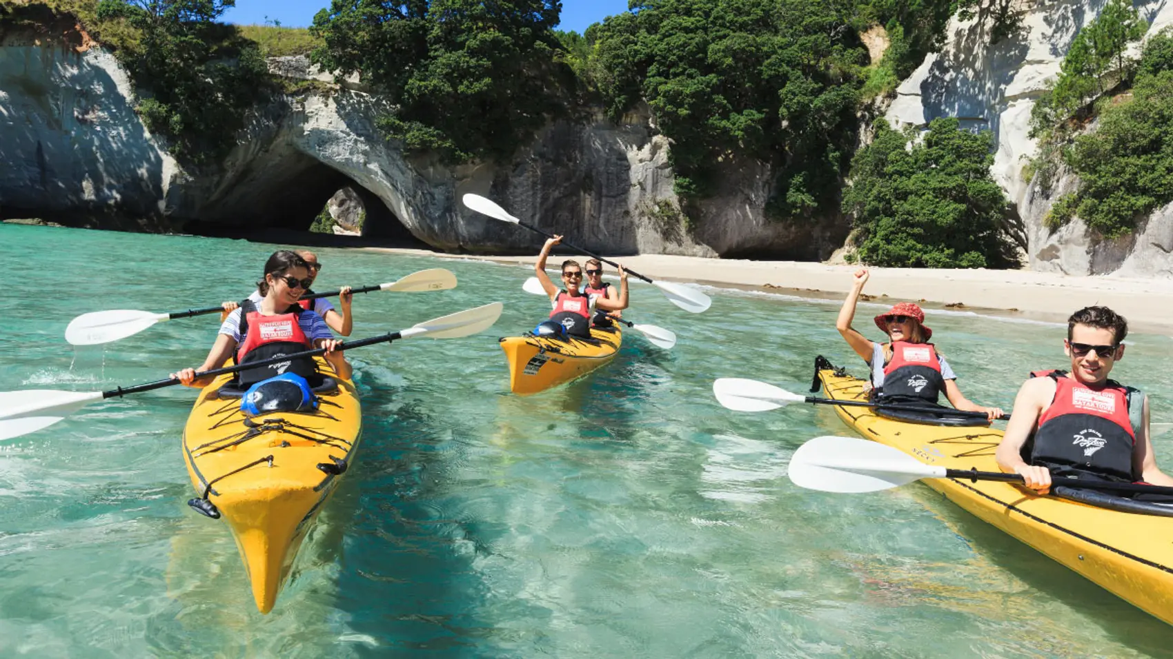 Group of people kayak in Cathedral Cove in New Zealand