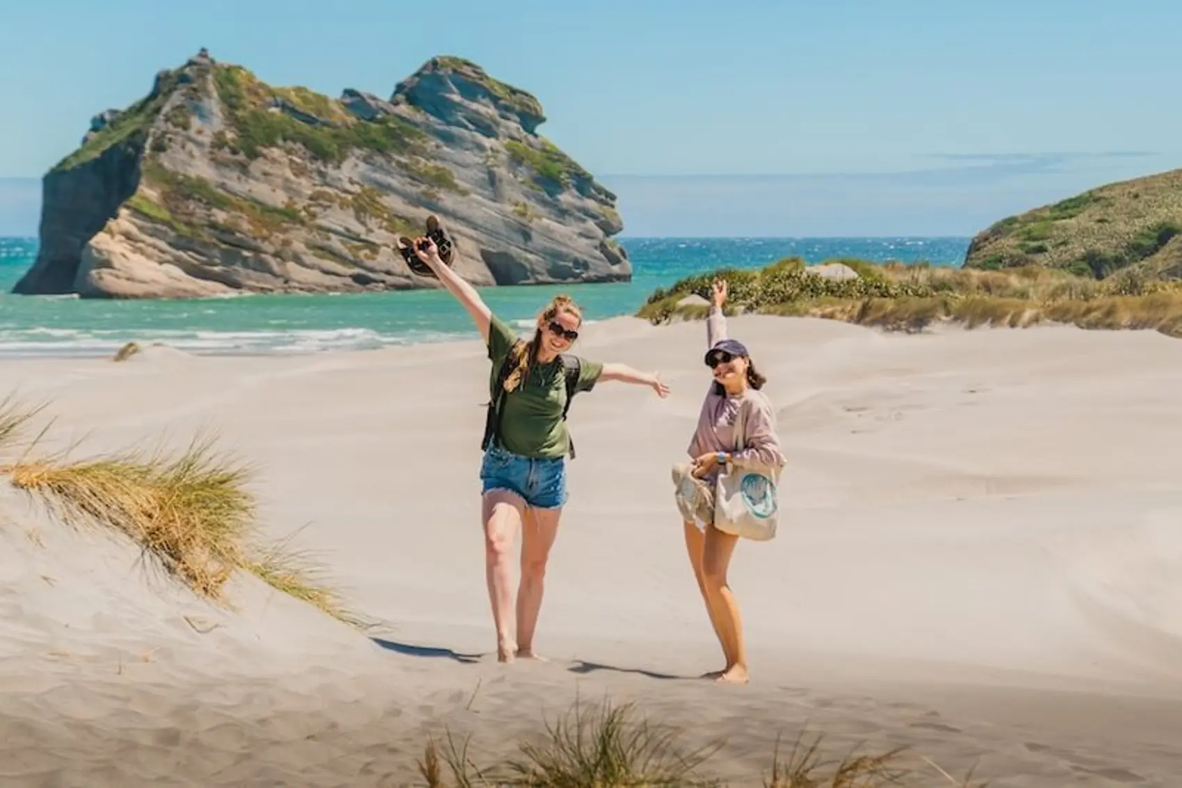 Two females on Golden Bay sand dunes happy and enjoying summer in New Zealand.