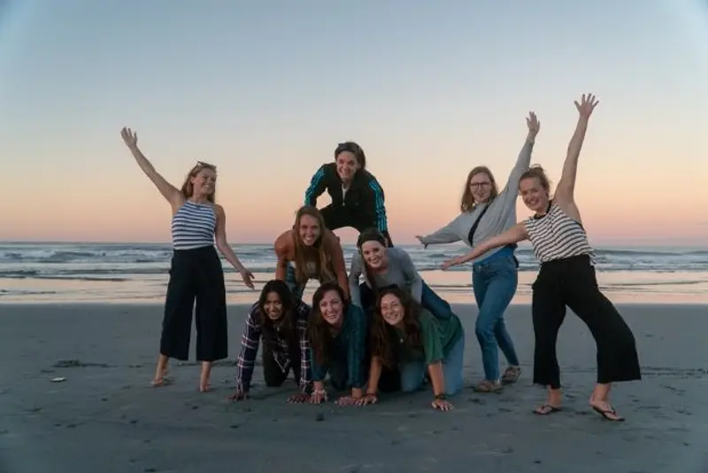 Group of Wild Kiwi guests making human pyramid on the beach