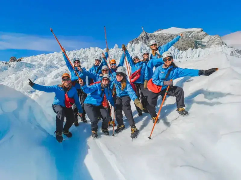 Group of travellers in glacier hiking gear exploring an icy glacier landscape in New Zealand, highlighting Franz Josef Glacier as an adventurous winter activity on the South Island beyond skiing.