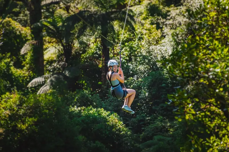 A girl zip-lining through native bush in Rotorua New Zealand.