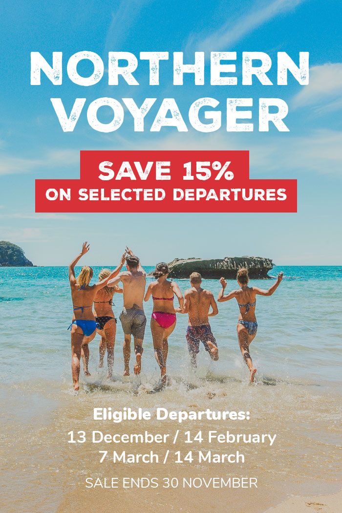 Group of people running into the water at Cathedral Cove