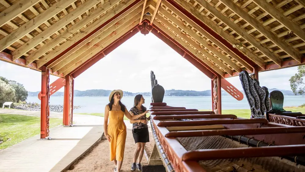 Two people looking at a waka canoe 