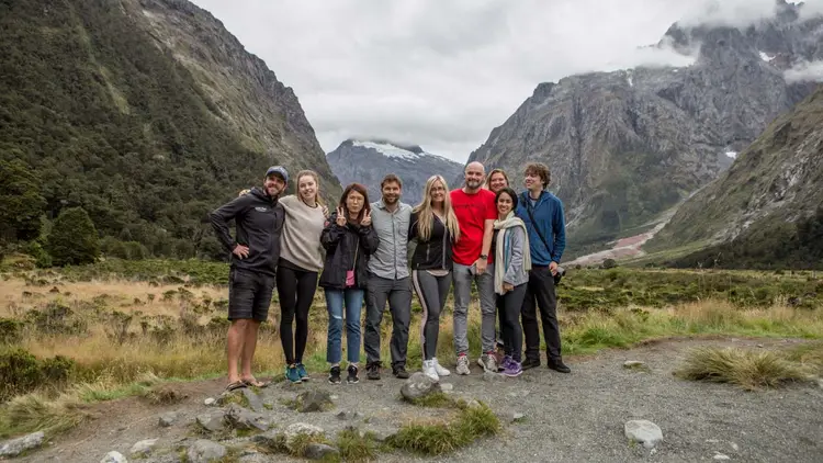 Group of surfing friends jump in the air on a beach in New Zealand