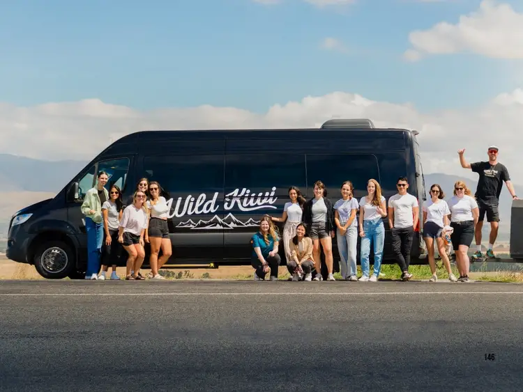 Group of people standing in front of a Wild Kiwi bus