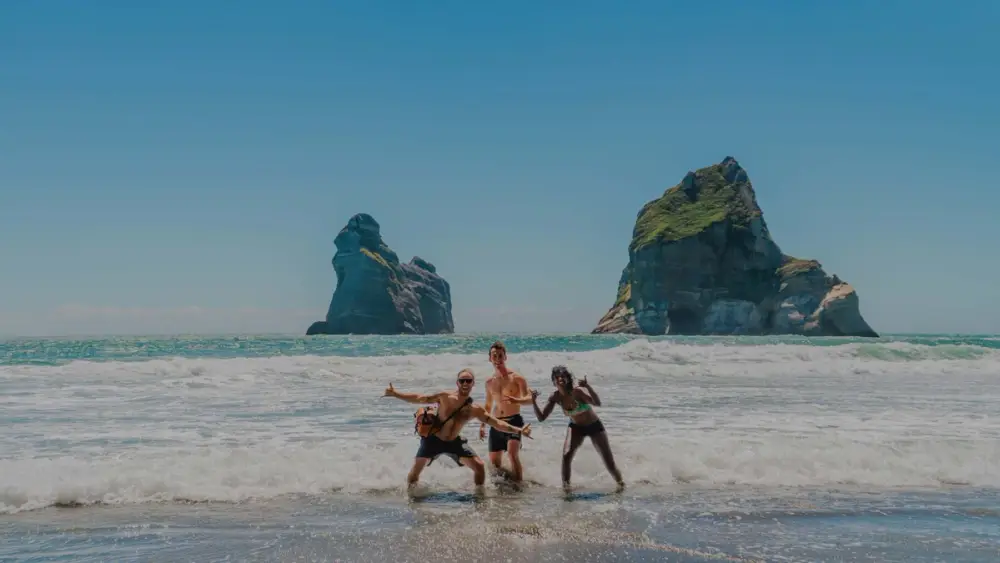Group of friends pose for a photo on Wharariki Beach