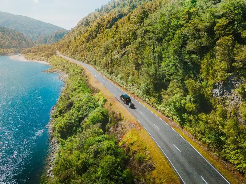Photo of a New Zealand adventure tour van on a lush highway in the South Island.