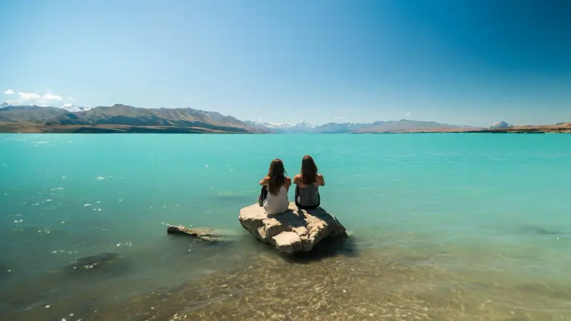 Two women sitting on a rock at Lake Yekapo