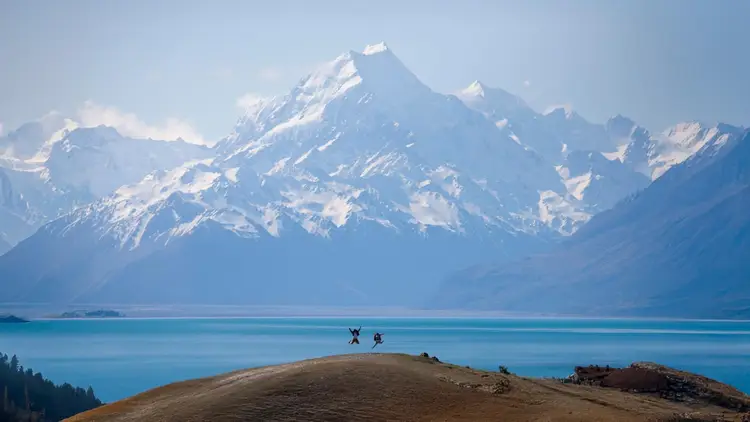 Two people posing jumping into the air in front of Mount Cook