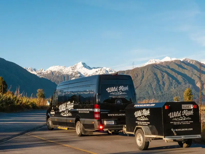 Photo of a luxury tour vehicle in New Zealand with snowy mountain peaks in the background.
